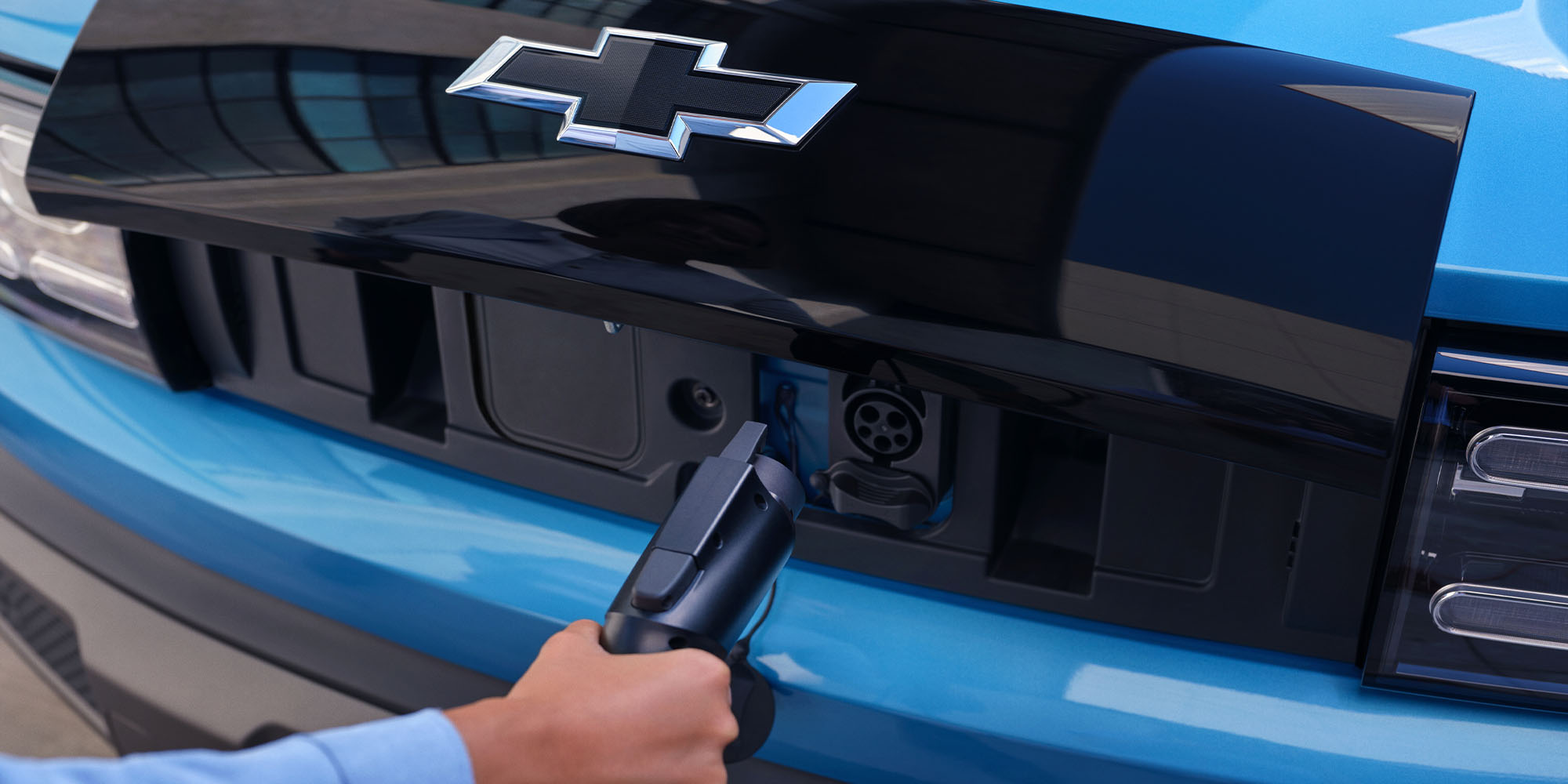 Chevrolet Spark EV color azul siendo cargado, vista de la entrada de carga